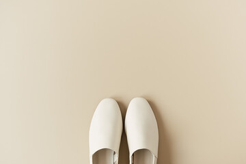 Fashion collage with women's white leather slippers on neutral beige. Minimal flat lay, top view lifestyle concept.