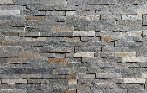 Stone wall cladding made of horizontal gray, brown and white strips of rock stacked . Background and texture
