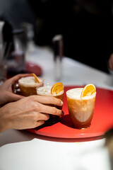 Manos cogiendo cocktail de caf&eacute; con adorno de naranja