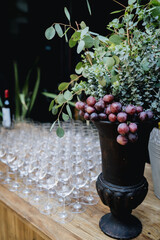 Centro de mesa adornado con uvas y copas vac&iacute;as de catering