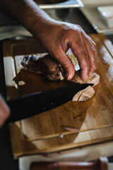 Cocinero cortado carne sobre tabla de madera en la cocina