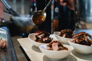 Chef echando salsa a plato de carne en salsa
