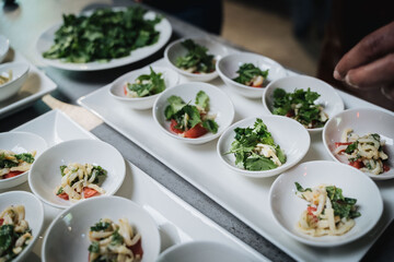 Detalle de catering con platos individuales de ensalada encima de una mesa