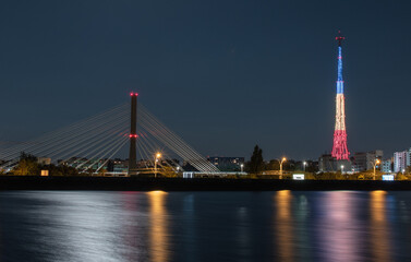 Light reflections in the water of the Mill Lake, coming from the tricolor illuminated tower, the street lighting and the road bridge