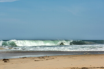 The big breaking waves during a strom at the beautiful summer sea shore background the blue sky and...