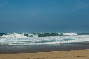 The big breaking waves during a strom at the beautiful summer sea shore background the blue sky and...