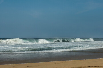 The big breaking waves during a strom at the beautiful summer sea shore background the blue sky and...
