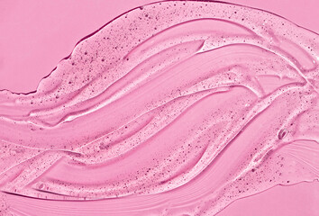 Transparent skin care product. Liquid gel cosmetic on pink background. Cosmetic clear liquid cream smudge. 