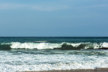 The big breaking waves during a strom at the beautiful summer sea shore background the blue sky and...
