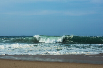 The huge waves crashing into ston island against the blue sky and horizon at summer sea shore.
