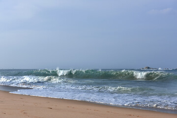 The huge waves crashing into ston island against the blue sky and horizon at summer sea shore.