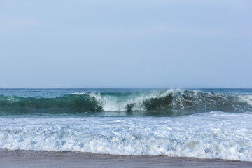 The huge waves crashing into ston island against the blue sky and horizon at summer sea shore.