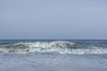 The huge waves crashing into ston island against the blue sky and horizon at summer sea shore.