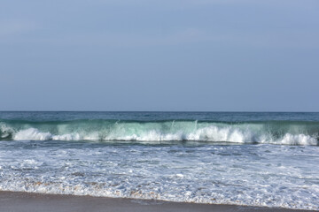 The huge waves crashing into ston island against the blue sky and horizon at summer sea shore.