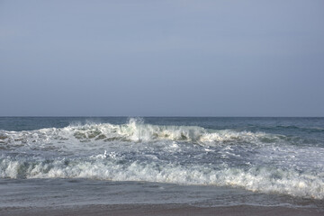 The huge waves crashing into ston island against the blue sky and horizon at summer sea shore.