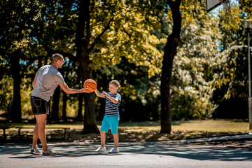 Cute blond boy practicing basketball with his coach