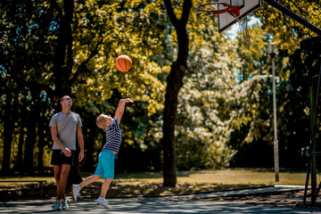 Cute blond boy practicing basketball with his coach