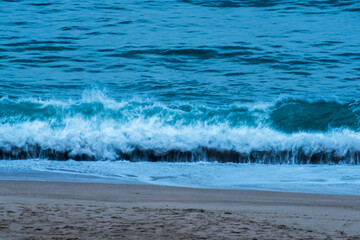 The huge waves crashing into ston island against the blue sky and horizon at summer sea shore.