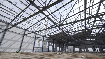 Construction of modern factory or warehouse, modern industrial exterior, panoramic view. Modern storehouse construction site, structural steel structure of new commercial building