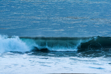 The huge waves crashing into ston island against the blue sky and horizon at summer sea shore.