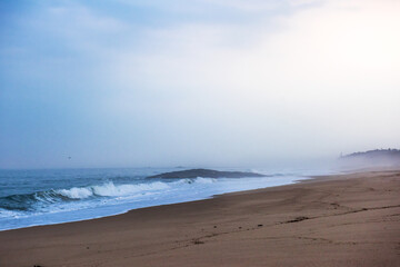 The huge waves crashing into ston island against the blue sky and horizon at summer sea shore.