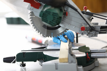 The carpenter puts a wooden block for sawing. Worker uses high-performance electric saws