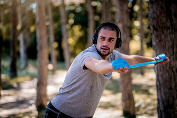 Young man exercising with elastic band outdoors 