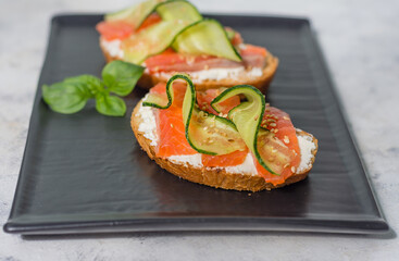 Open sandwiches with cream cheese, trout and cucumber on a plate horizontal view