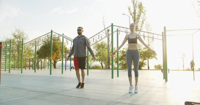 caucasian male with his personal coach young sporty female exercising outdoors in the morning. Healthy active lifestyle concept.