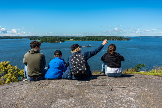 Family sitting on a mountain top overlooking the water of the sea Malaren against the horizon.