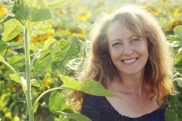 Portrait of happy mature woman  enjoying of freedom in the sunflowers field