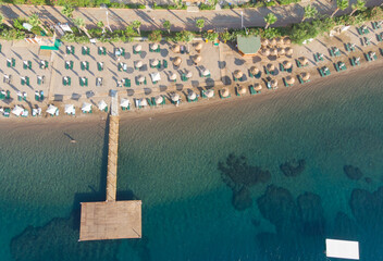 Fototapeta premium Aerial view of amazing tropical beach with white umbrellas and turquoise sea. Top down aerial view beautiful beach
