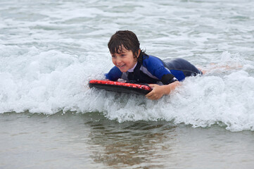 Obraz premium Child swimming with bodyboard on the sea waves.