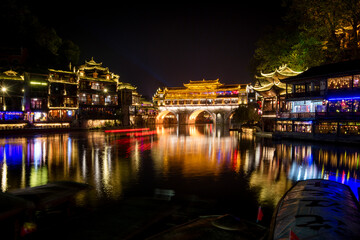 Fototapeta na wymiar View of illuminated at night riverside houses in ancient town of Fenghuang known as Phoenix, China