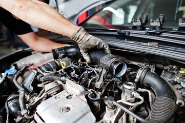 Obraz na płótnie Canvas Car repair and maintenance theme. Mechanic in uniform working in auto service, checking engine.