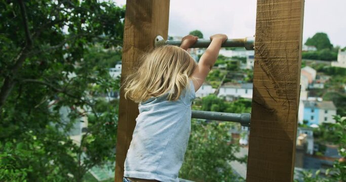 Preschooler climbing and hanging from bars of calisthenics gym