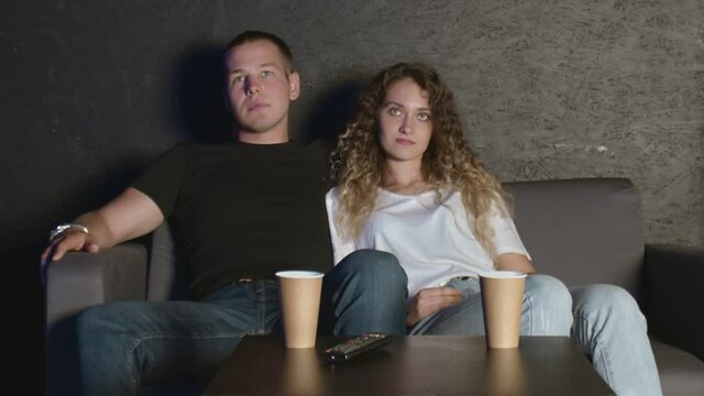 A couple of lovers watch television embraced on the sofa. watch a movie together.