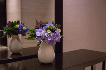 Bouquet of purple hydrangea stands in a white vase by the mirror