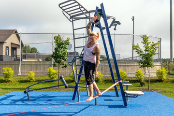 blond woman walking on a tightrope slackline at the park in Saguenay Quebec Canada