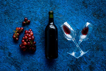 Red wine with grape - in glasses and bottle - on blue desk top view
