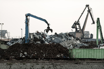 A crane with grippers in action on recycling yard.