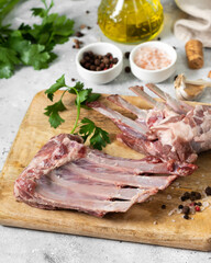 Lamb meat. Lamb ribs on a wooden chopping Board on the light gray kitchen table. Raw meat of a young lamb on the table	
