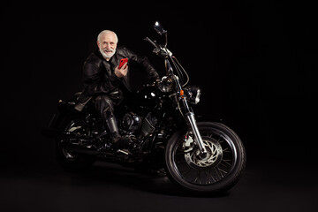 Full size photo of positive cool old man biker sit bike use smartphone search vacation adventure...