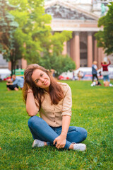 A cute girl with long brunette hair relaxes on the grass in the center of St. Petersburg in front of St. Isaac's Cathedral