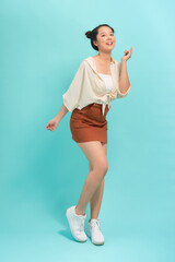 Full length portrait of a cheerful beautiful girl having fun isolated over blue background