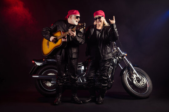 Photo of aged cool bikers man lady couple chopper moto feel young rock bike festival meeting play sing guitar show horns wear trendy rocker leather outfit isolated black color background