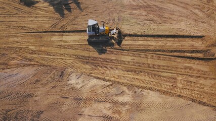 Planierraupe, Kettenraube, Bulldozer schiebt Fläche mit Sand auf einer Baustelle ab,...