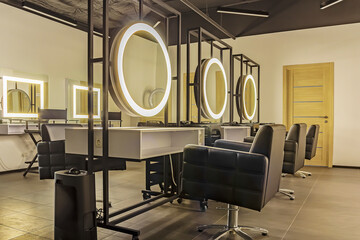 Modern barber shop. Interior of beauty salon, hairdresser workplace. Premium coworking center for hair masters: workplace of the hairdresser with illuminated mirrors and comfortable chairs
