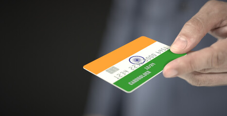 Man gives plastic bank card with printed flag of India. Fictional numbers