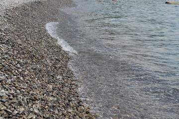 The sea waves beat against the shore. White foam waves of the sea. Pebble beach beach